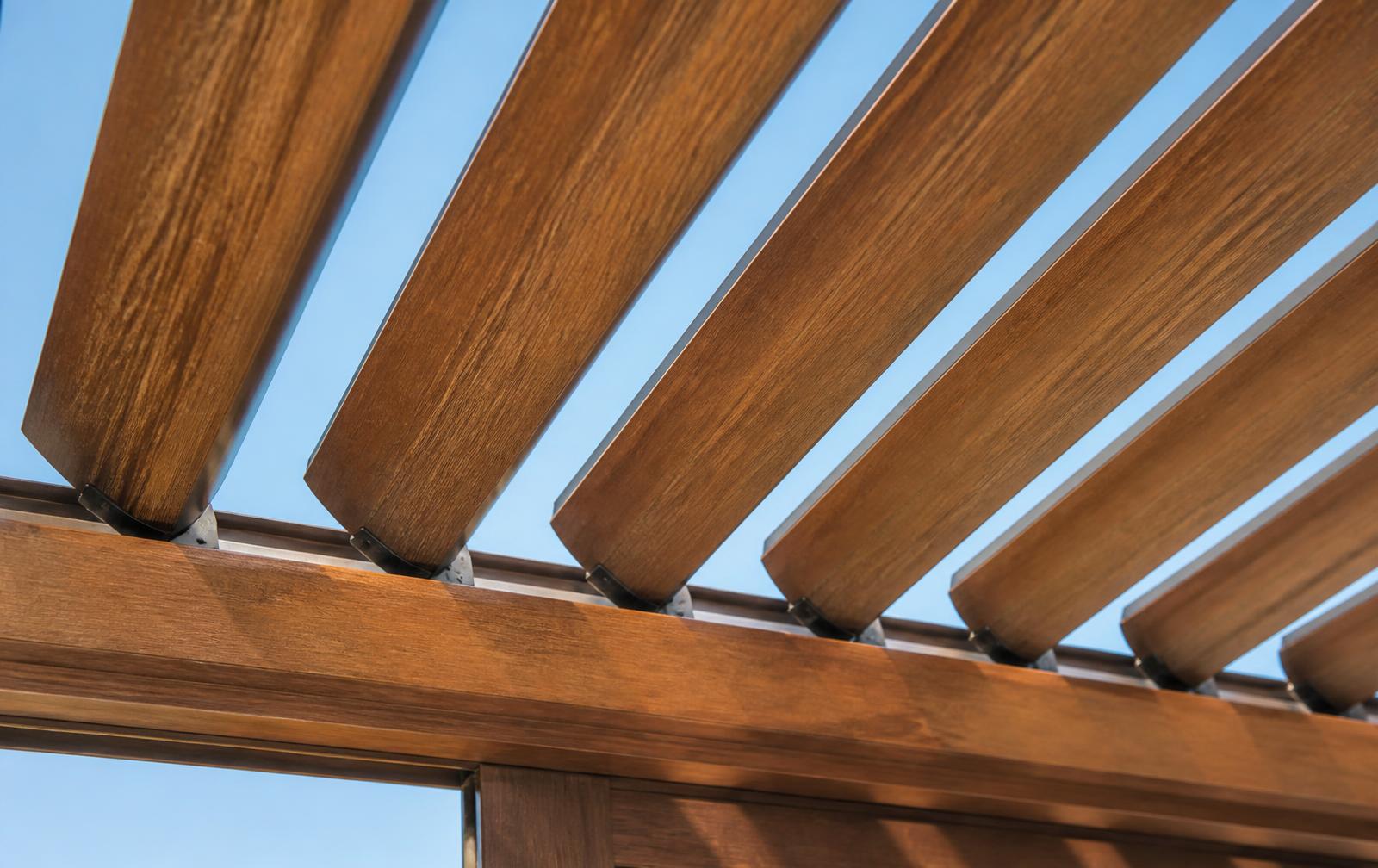 Cedar Wood Grain finish on adjustable aluminum patio cover louvers tilted against a blue sky